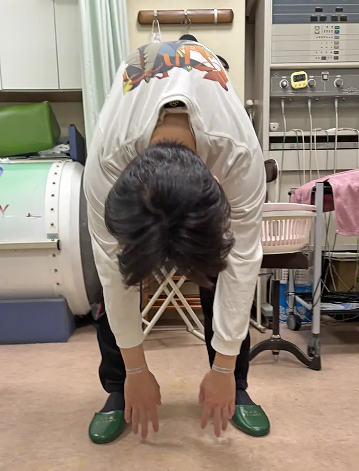24歳会社員。体幹矯正施術で前屈姿勢で指が床に近づいた。